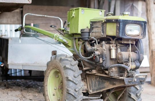 Typical heavy diesel walking tractor with trailer. Agricultural transport equipment of the countryside. Portable agricultural equipment, walking minitractor. The start system is mechanical and manual