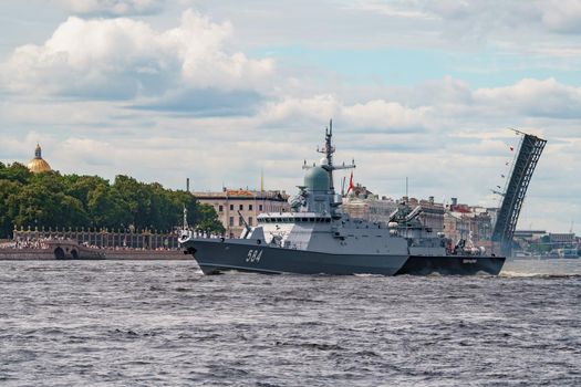 Russia, St. Petersburg, 28 July 2022: A huge warship goes along the Neva River under open bridges at the time of the rehearsal of the celebration of the day of the Navy in sunny weather. High quality photo