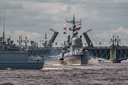 Russia, St. Petersburg, 28 July 2022: A lot of warships goes along the Neva River under open bridges at the time of the rehearsal of the celebration of the day of the Navy in sunny weather. High quality photo