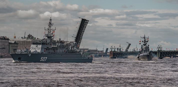 Russia, St. Petersburg, 28 July 2022: A lot of warships goes along the Neva River under open bridges at the time of the rehearsal of the celebration of the day of the Navy in sunny weather. High quality photo