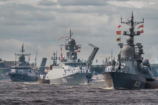 Russia, St. Petersburg, 28 July 2022: A lot of warships goes along the Neva River under open bridges at the time of the rehearsal of the celebration of the day of the Navy in sunny weather. High quality photo