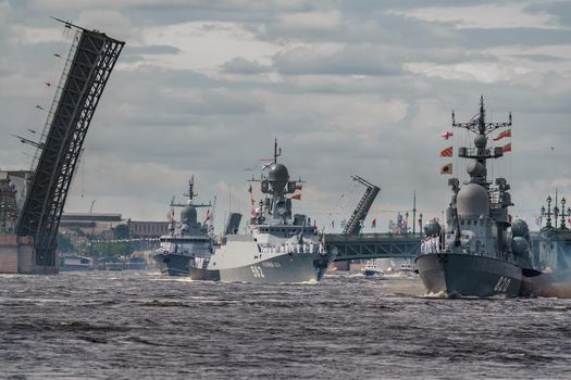 Russia, St. Petersburg, 28 July 2022: A lot of warships goes along the Neva River under open bridges at the time of the rehearsal of the celebration of the day of the Navy in sunny weather. High quality photo
