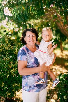 Aged woman holding a little girl in her arms. High quality photo