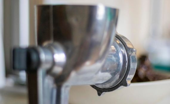 The classic manual iron meat grinder is fixed on the table. Antique, vintage meat grinder in the kitchen, close-up. The meat grinder is ready to go