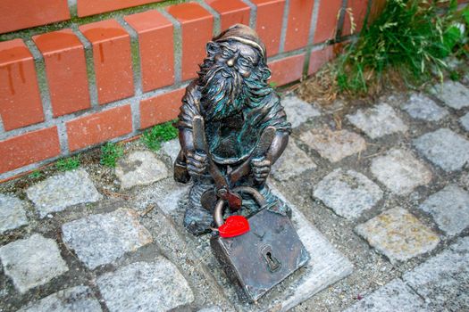 Dwarf gnomes sculpture with magnifying glass in downtown of famous polish city. Wroclaw Houses and streets of the city of Wroclaw. Cityscape. High quality photo