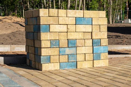 stacks of new colored paving slabs for paving paths stacked on a construction site in a city park. improvement of the city, paving of sites