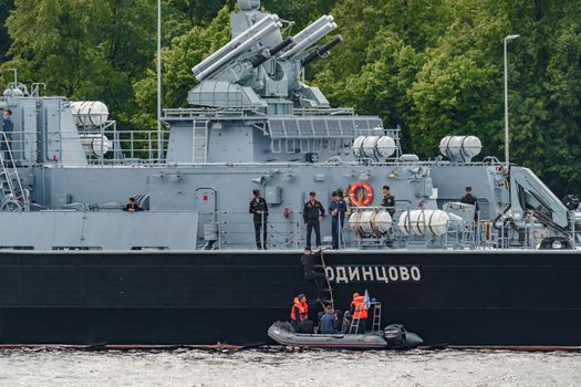 Russia, St. Petersburg, 28 July 2022: A several modern warships anchored at the Neva River embankment during the Navy Day celebrations in sunny weather, sailors on deck in festive uniforms. High quality photo