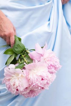 bride in a blue wedding dress with a bouquet of pink peonies, pastel paradise, floral background, complementary color combination. High quality photo
