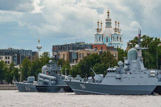 Russia, St. Petersburg, 28 July 2022: A several modern warships anchored at the Neva River embankment during the Navy Day celebrations in sunny weather, sailors on deck in festive uniforms. High quality photo