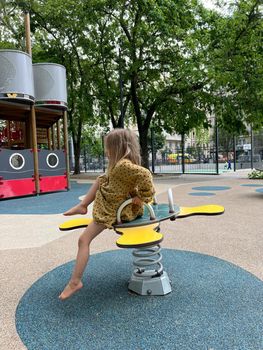 Little girl sits on a swing in the playground. High quality photo