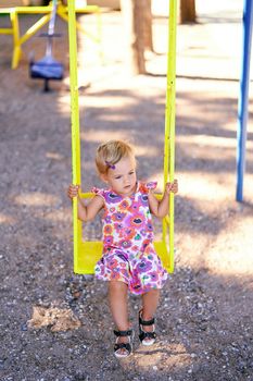 Little girl on a swing in the playground. High quality photo