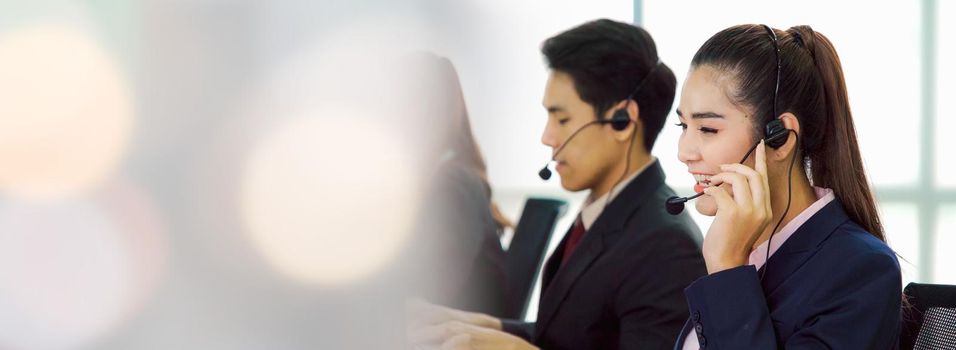 Business people wearing headset working in office in widen view to support remote customer or colleague. Call center, telemarketing, customer support agent provide service on telephone video call.