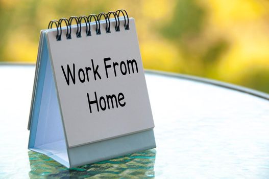 Work from home text on white calendar table with blurred nature background. Work from home concept