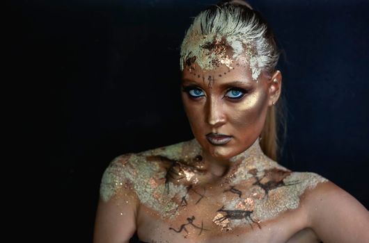 Portrait of female model with creative prehistoric makeup with cave painting