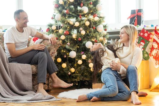 Christmas. Family. Happiness. Top view of dad, mom and daughter on the floor at home