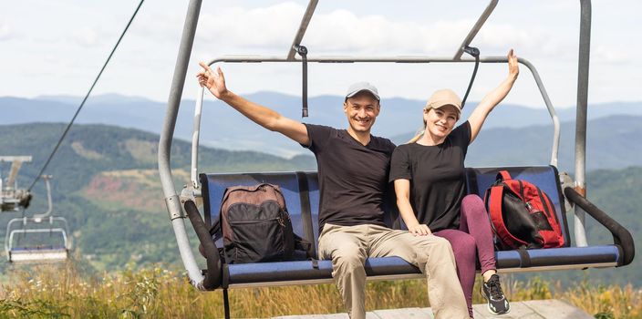 Man and a woman riding on the lift down the scenic Mountain during summer. Green tree forest surrounds the escalator