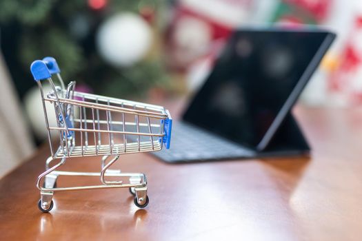 toy trolley and a Christmas tree on background. Copy space - concept of online shopping, ordering goods, home delivery, new year 2023, decoration, preparation.