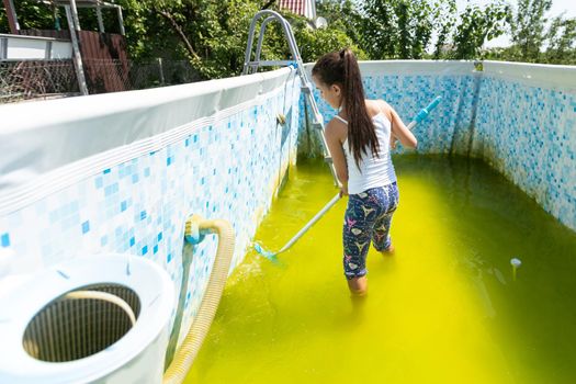 Back yard swimming pool behind modern single family home at pool opening with green stagnant algae filled water before cleaning