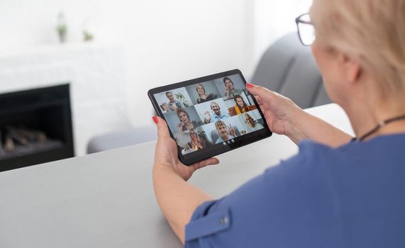 Senior woman making video call from tablet computer at home.