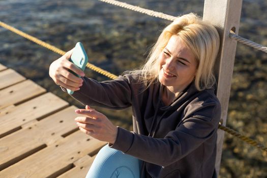 Middle aged woman on the beach talking online using smartphone