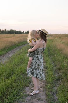 Mom and daughter walk through a chamomile field, and collect a bouquet of flowers. The concept of family relations, nature walks, freedom and a healthy lifestyle.