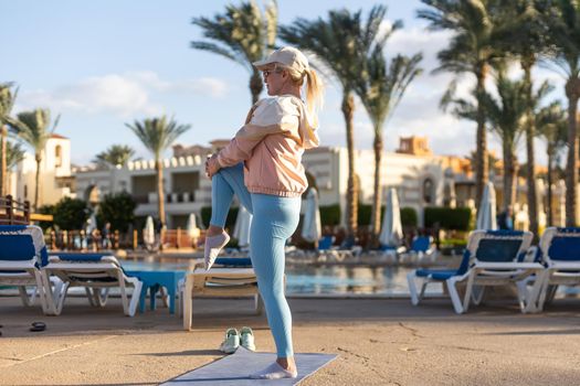 fit athlete woman making stretching exercises open air tropical yard villa swimming pool, Early morning Hotel resort vacation, Health care, wellbeing.