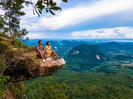 Dragon Crest mountain Krabi Thailand, a Young traveler sits on a rock that overhangs the abyss, with a beautiful landscape. Dragon Crest or Khuan Sai at Khao Ngon Nak Nature Trail in Krabi, Thailand