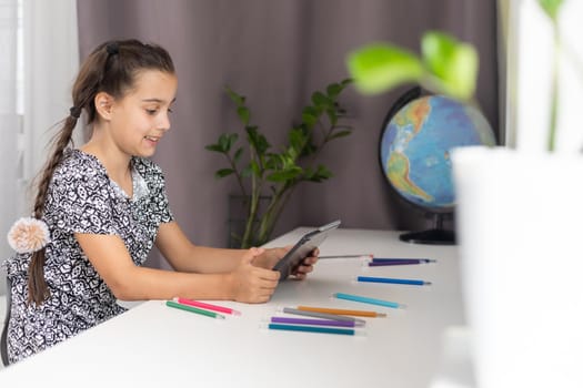 Happy little girl reading while using digital tablet in the room