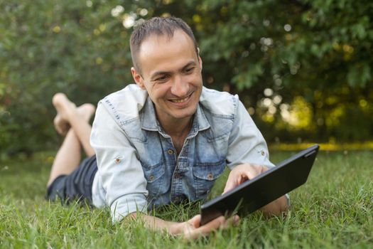 a man uses a tablet to chat in the garden.