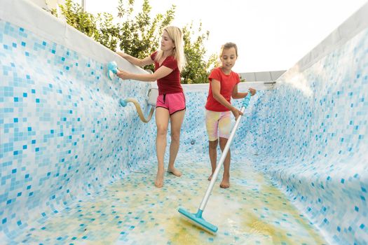 mother and daughter cleaning swimming pool in the garden.
