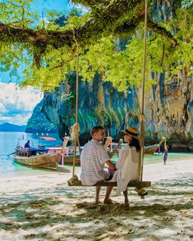 Koh Lao Lading near Koh Hong Krabi Thailand, beautiful beach with longtail boats, a couple of European men, and an Asian woman on the beach.