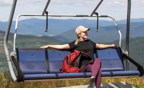 Beautiful woman tourist is sitting in the open cabin of the cable car. Funicular lift. Transport lift to the mountains. summer tourism.