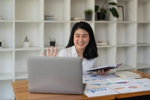 Cheerful businesswoman making a video call with laptop computer in office.