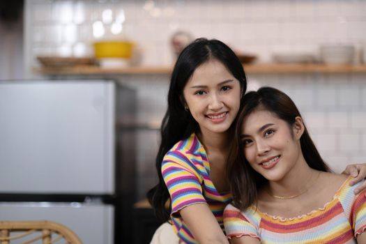 Portrait of a smiling young lesbian couple hugging each other while standing together at home.