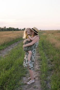 Mom and daughter walk through a chamomile field, and collect a bouquet of flowers. The concept of family relations, nature walks, freedom and a healthy lifestyle.