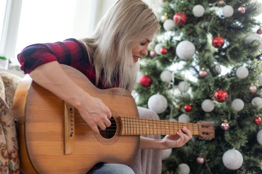 Young woman playing guitar on Christmas holidays. Hygge concept. musician, hobby, lifestyle.
