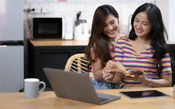 Portrait of young Asian female lovers reading book and spending happy time together, LGBT concept.