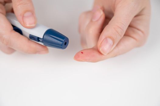 Caucasian woman doing a glucose test using a pen lancet