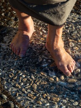 Woman barefoot standing on stone floor background.