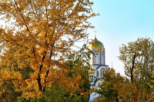 Autumn is the most colorful time of the year, when nature changes its usual appearance to golden colors in glimpses. Trees with orange yellow leaves and a white church with golden domes.