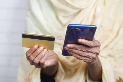 senior women hand holding credit card and using smart phone shopping online .
