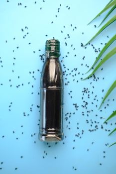 Black Cumin seeds and oils in a container on blue background ,