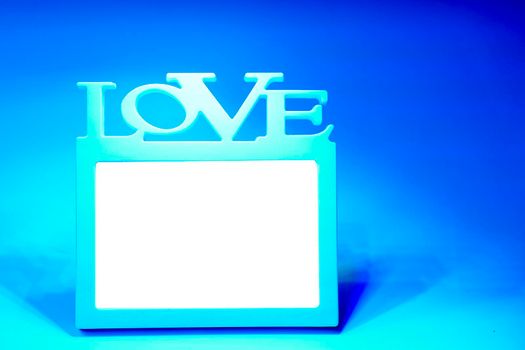 a rigid structure that surrounds or encloses something such as a door or window. White frame with the inscription love on a blue background. High quality photo
