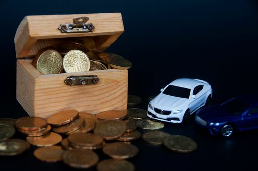 Kuala Lumpur, Malaysia - July 2022 : Miniature toy car of Mercedes AMG and Bentley Continental GT with gold coins and treasure chest on black cover background. Wealth concept
