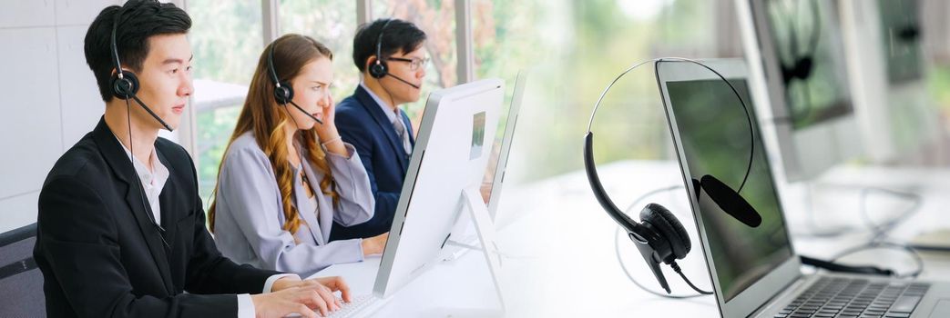 Business people wearing headset working in office in widen view to support remote customer or colleague. Call center, telemarketing, customer support agent provide service on telephone video call.