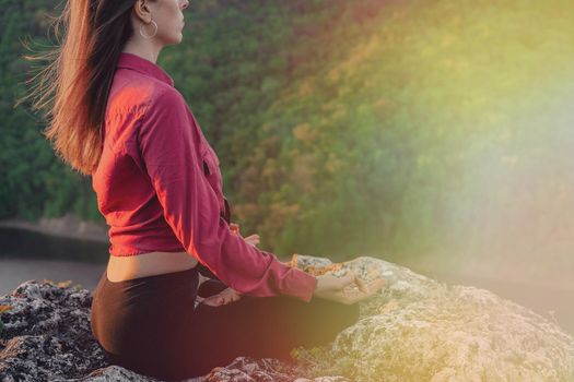 Peaceful yogi woman sitting in lotus, meditating, feeling free in front of wild nature. Mindful fitness coach having zen moment. Everyday yoga practice, calm breath, concentration concept.High quality