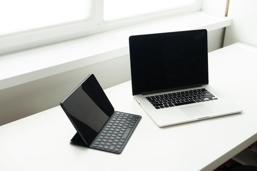 laptop and tablet on a white table.