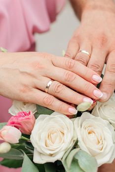 the hands of the bride and groom with rings over a bouquet of flowers. photo