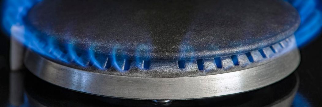 Combustion of natural gas, propane. Gas stove on a black background. Fragment of a gas kitchen stove with a blue flame, close-up. Energy crisis concept, rise in price or price of gas