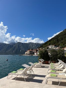 Sun loungers on the tiles of the embankment against the backdrop of mountains. High quality photo